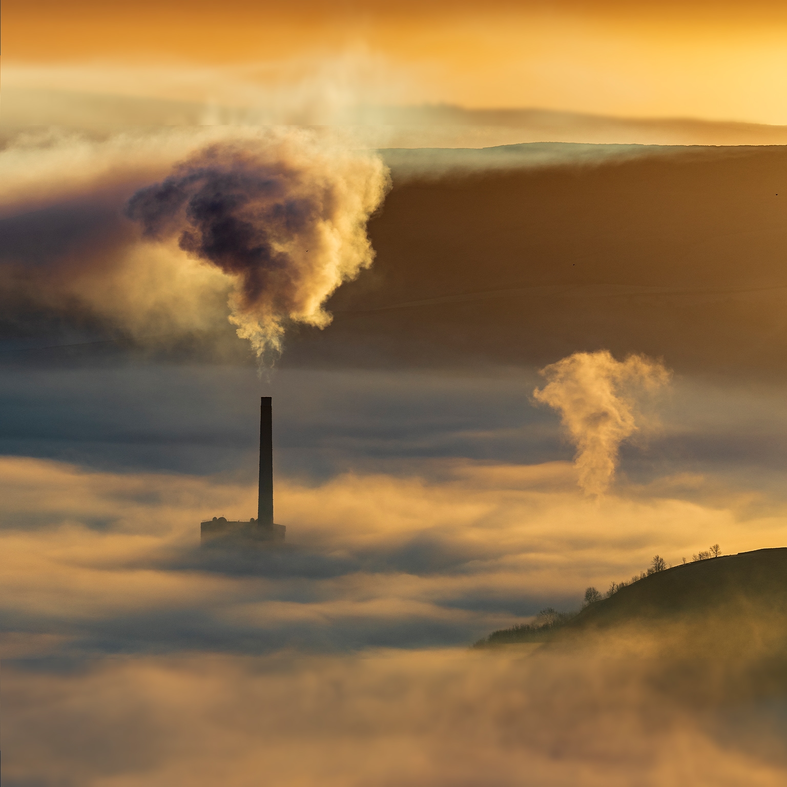Hope valley and Castleton on a stunning misty morning with the pollution of the local cement factory at sunrise. Peak District National park. Derbyshire. - stock photo