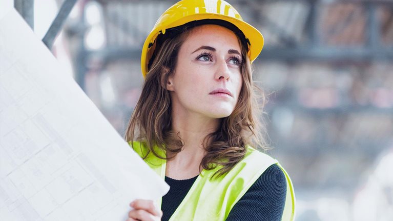 A female construction worker holds plans