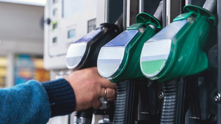 Refueling at a modern gas station with green fuel pumps and a customer filling their vehicle in a well-lit, organized space during daytime