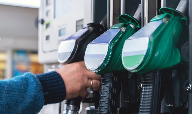Refueling at a modern gas station with green fuel pumps and a customer filling their vehicle in a well-lit, organized space during daytime