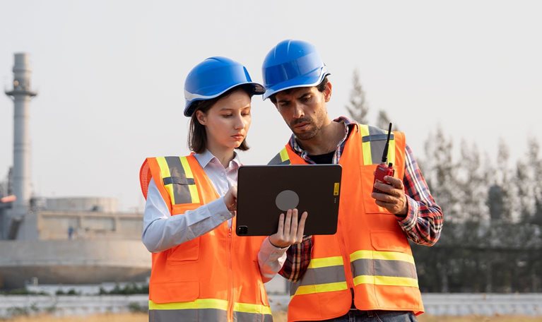 Male and Female Engineers working together in front of power plant factory