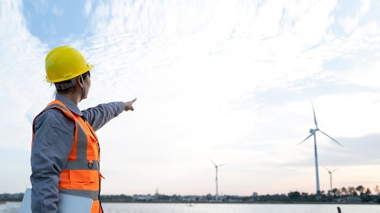 Female engineer manager finger in front of wind power station - stock photo