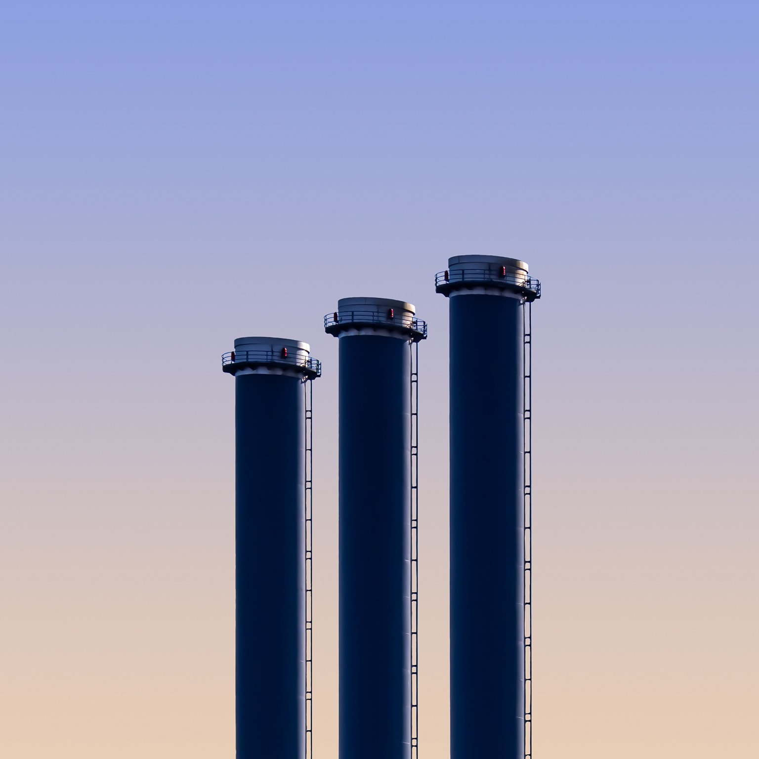 Three blue cylinders are standing in the middle of a field - stock photo