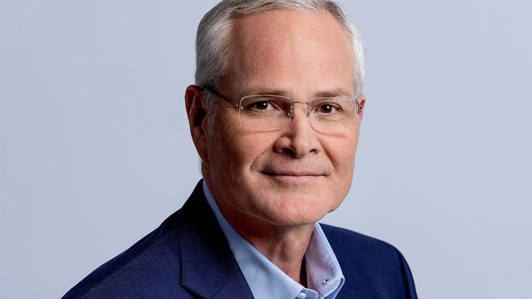 A headshot of Darren Woods smiling softly.