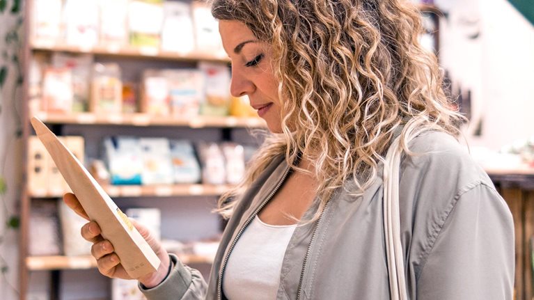 Woman looking at food products on the shelf of a local organic grocery store