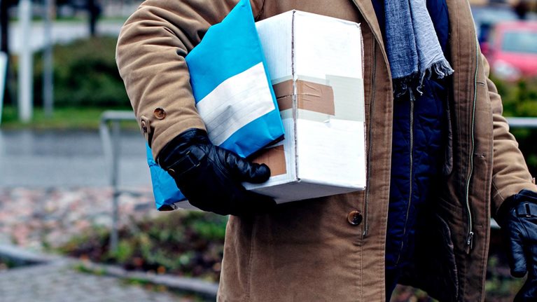 Midsection of senior man with package walking by sidewalk during winter - stock photo