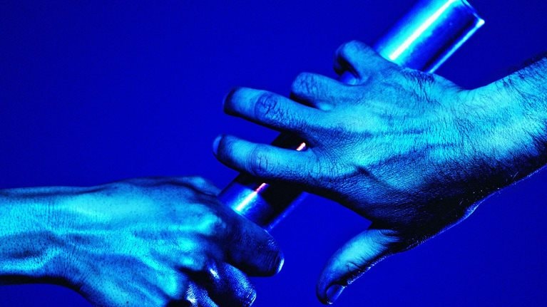 One hand passing a baton to the other