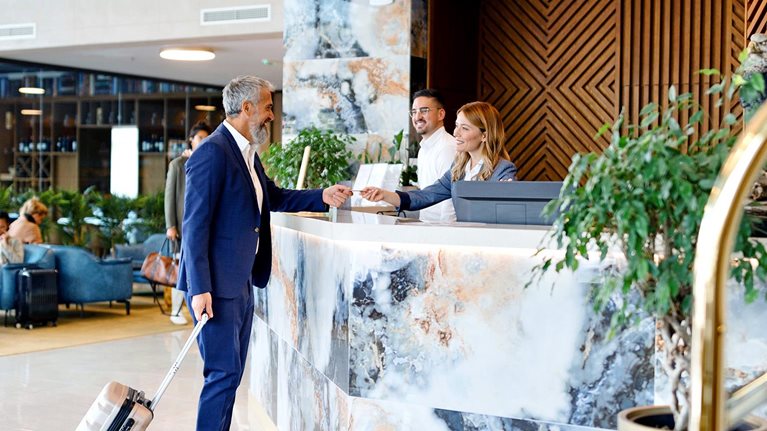 Elegantly dressed businessman talking with a receptionist while checking out from the hotel