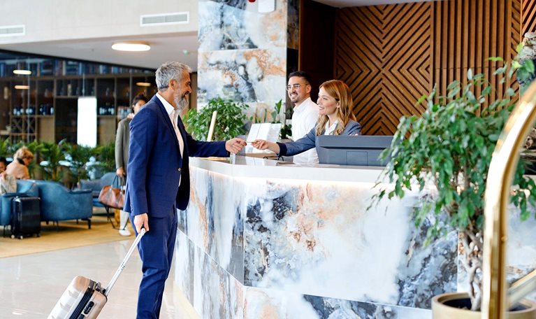 Elegantly dressed businessman talking with a receptionist while checking out from the hotel