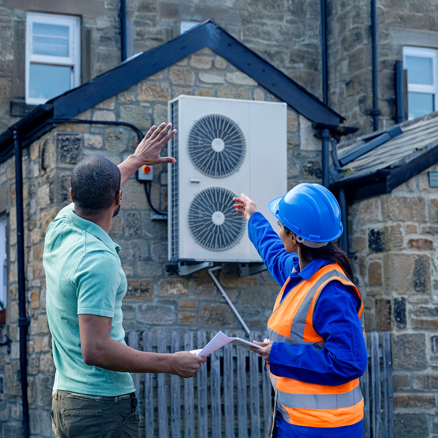 Customer and installation electrician stand outside of home to inspect an air source heat pump