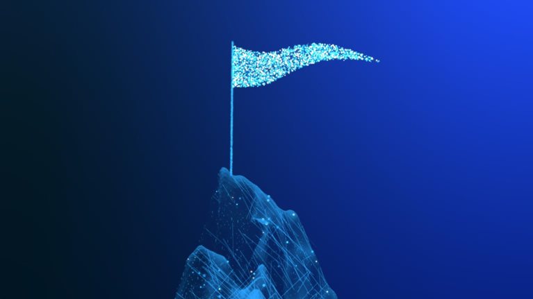 Animated blue particles form a mountain peak against a dark background. A flagpole rises from the summit, and a glowing blue flag waves as small particles drift away.