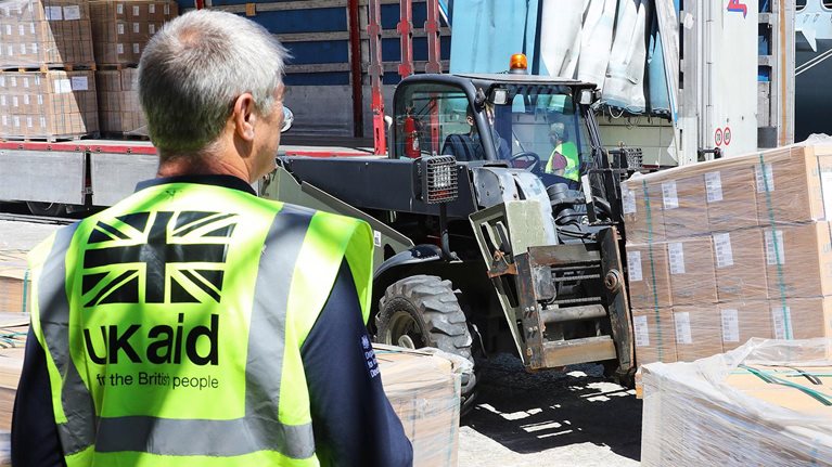 UK aid staff manage vital aid being loaded onboard HMS Ocean