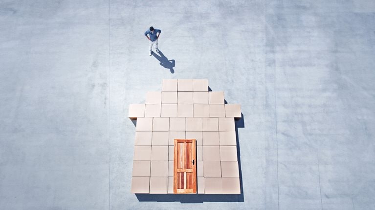 Man standing next to house outline on sidewalk - stock photo