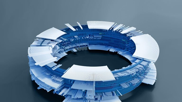 A circular structure composed of numerous small, rectangular blocks in shades of blue and white. The structure resembles a complex, futuristic computer component, with layers of blocks creating an intricate design.