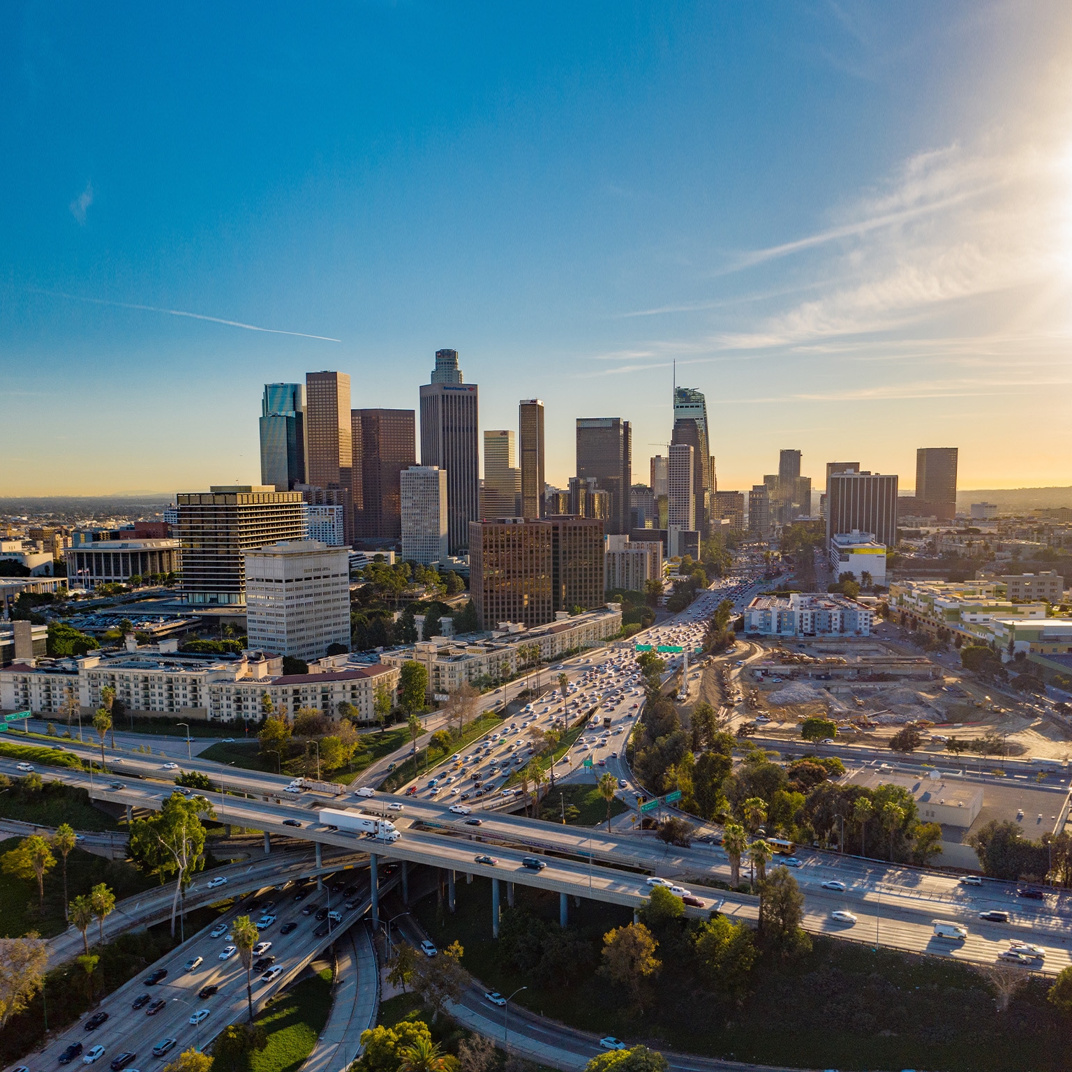 Drone view of downtown Los Angeles or LA skyline with skyscrapers and freeway traffic below.