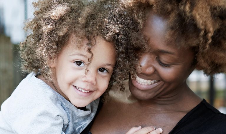 Smiling woman holding a happy child.