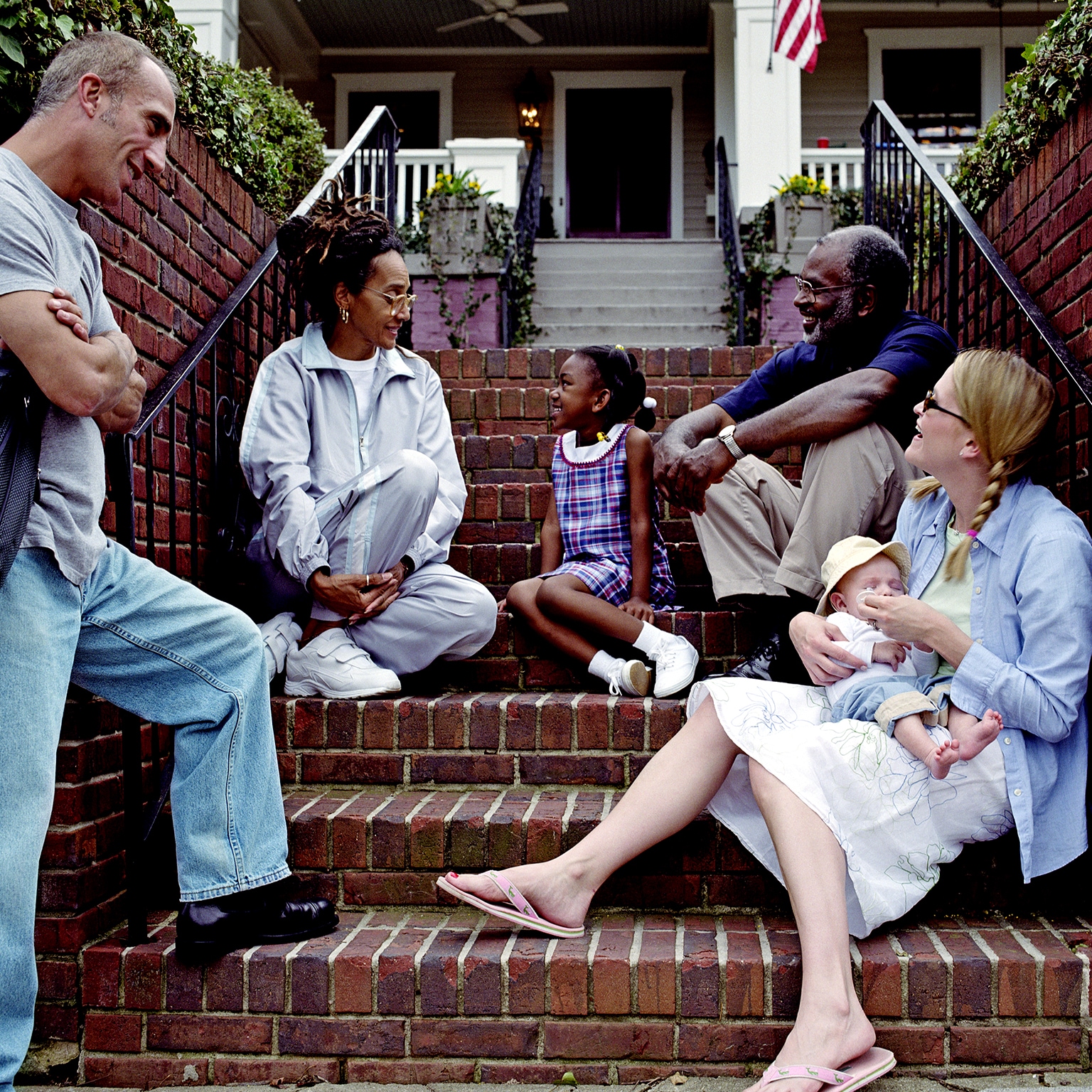 Men, women, and children catching up at the staircase to a home