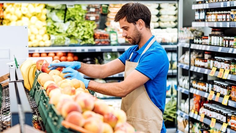 Employee in supermarket arranging fresh fruit