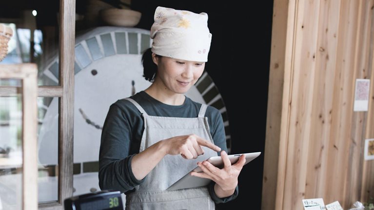 Woman using tablet computer in a small bakery