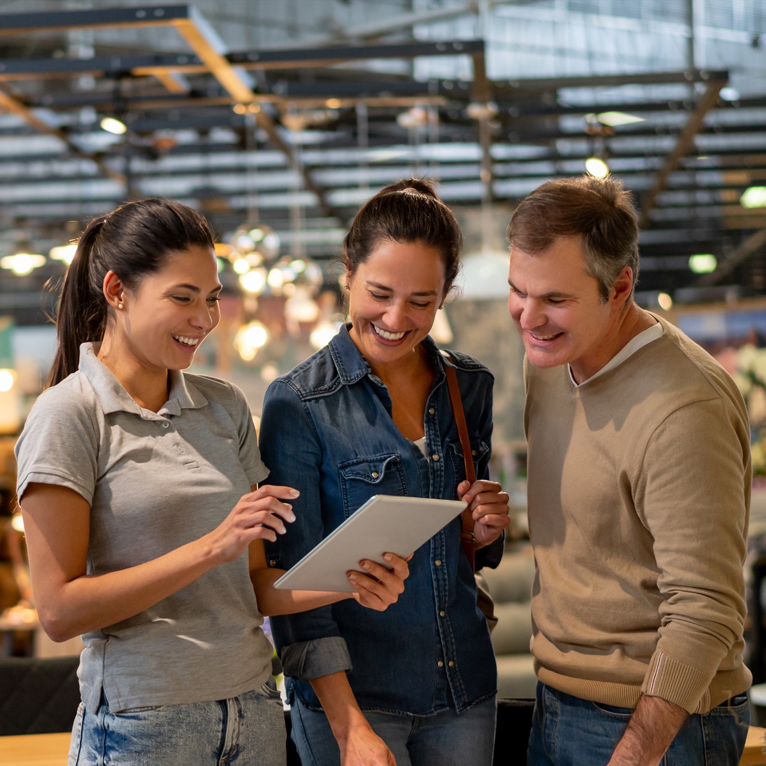 Middle aged couple in store being shown inventory on tablet by younger employee