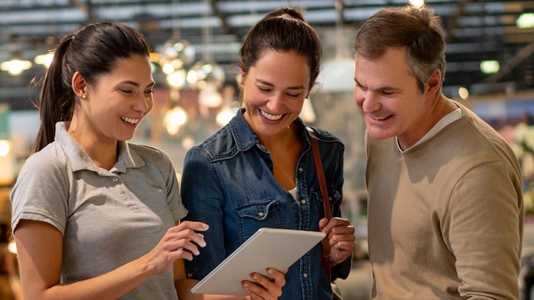 Middle aged couple in store being shown inventory on tablet by younger employee