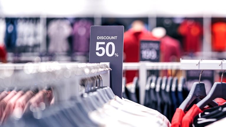 Discount 50% label of sales tag price over the clothes line in a shopping department store.