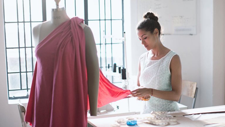 A photo of a women fixing a garment on a model