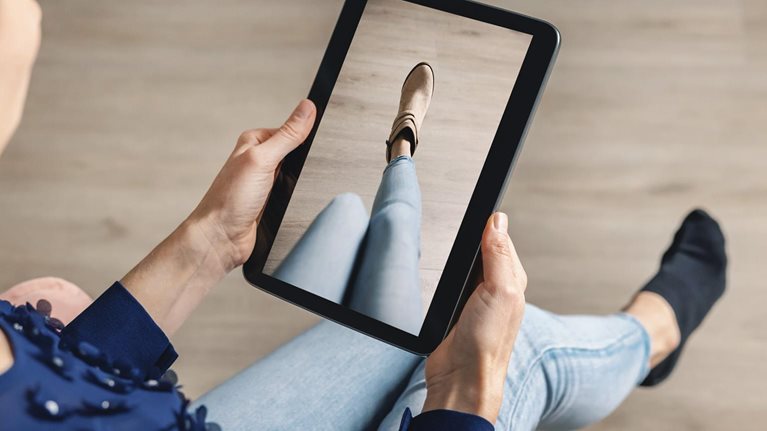 Woman trying on shoes online with digital tablet