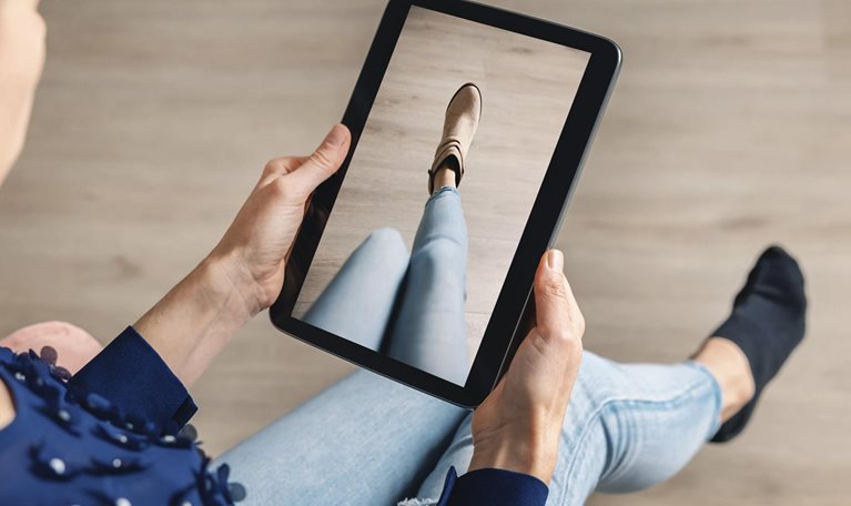 Woman trying on shoes online with digital tablet