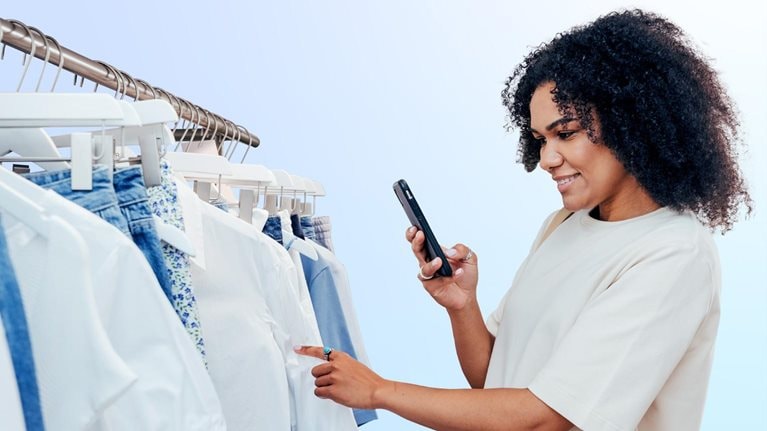 Side view of young woman photographing clothes in shop