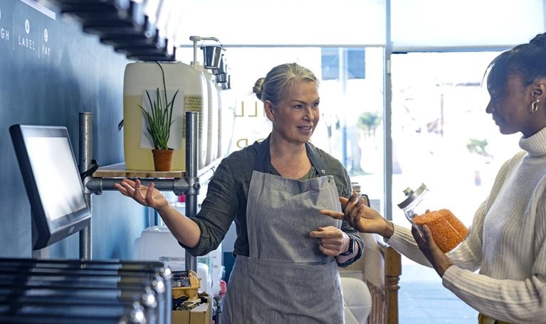 Image of an employee helping a customer at the self-checkout station.