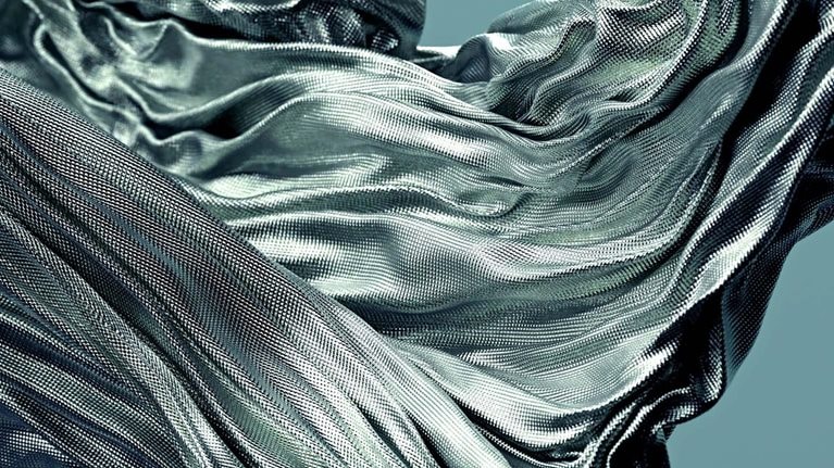 Fabric with a textured surface gracefully flowing and swirling in the air, creating dynamic folds and curves.
