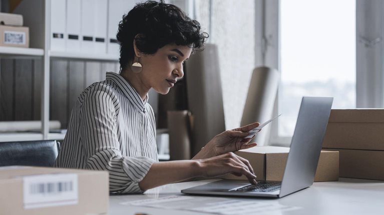A young small business owner using her laptop to check the customer's order details on her website