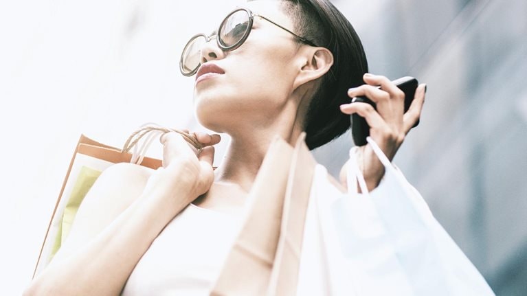 Woman using phone while shopping - stock photo