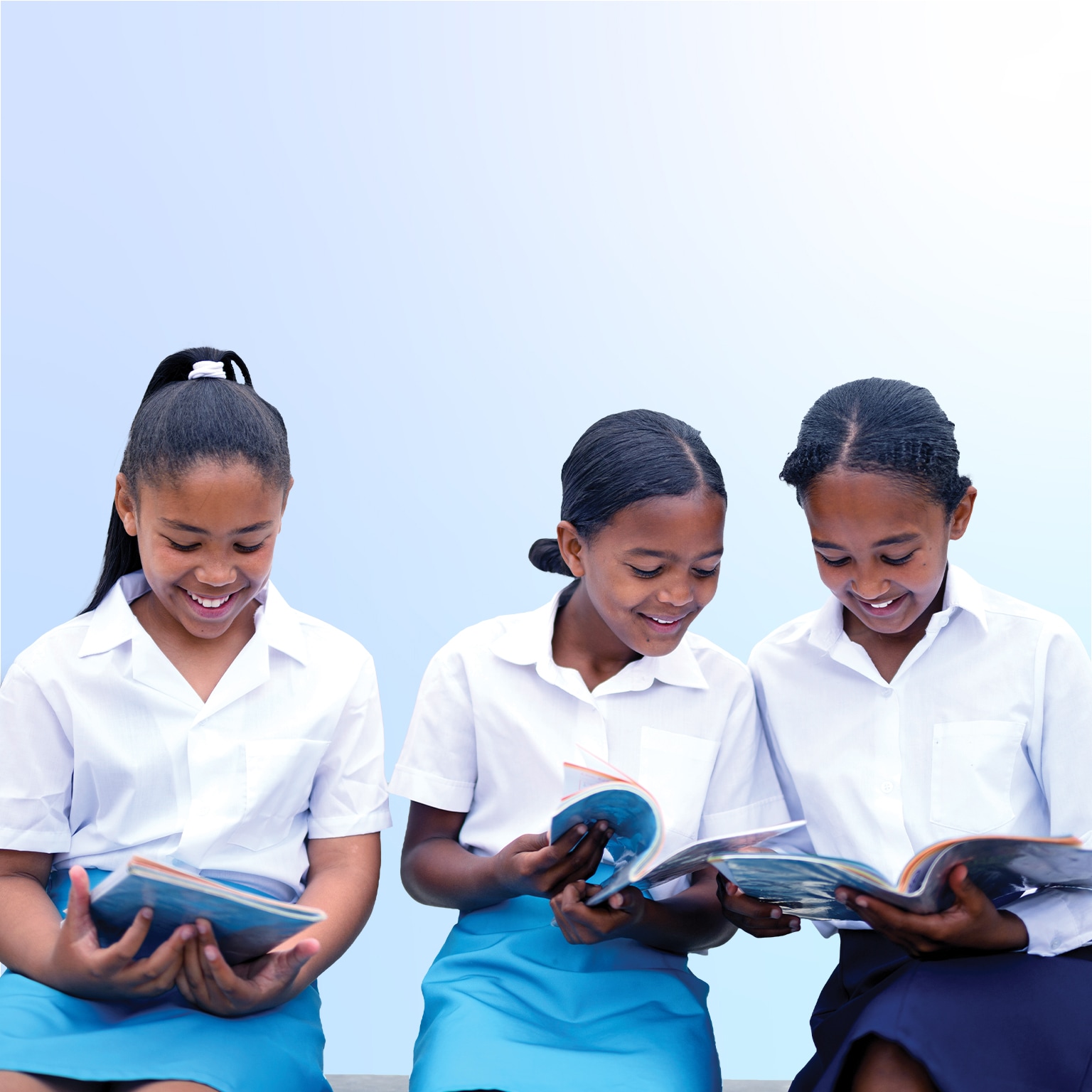 Schoolgirls looking through textbooks in school yard together