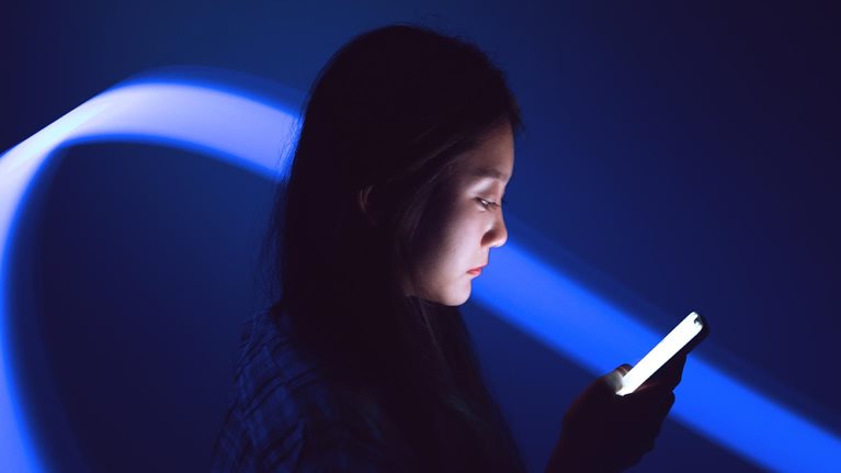 Young Asian woman using smartphone on the holographic background. Metaverse and AI - stock photo