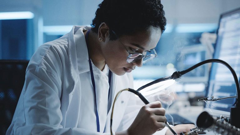 Black female engineer does computer motherboard soldering