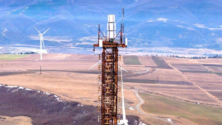 Communication tower and wind turbines on land in Georgia. Taken via drone. - stock photo