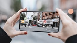 Young woman locating direction with augmented reality technology on smartphone on street.