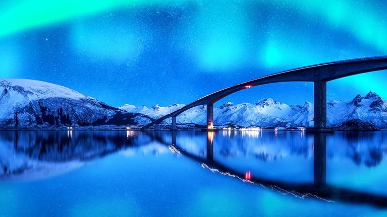 A Bridge and aurora borealis over snowy mountains