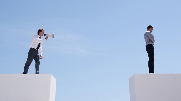 Businessman with megaphone on wall shouting at businessman on wall with gap