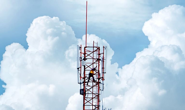 Telecommunication tower with backdrop of blue sky and white clouds