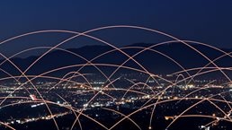 Multiple rays of light connecting buildings to each other across a city skyline