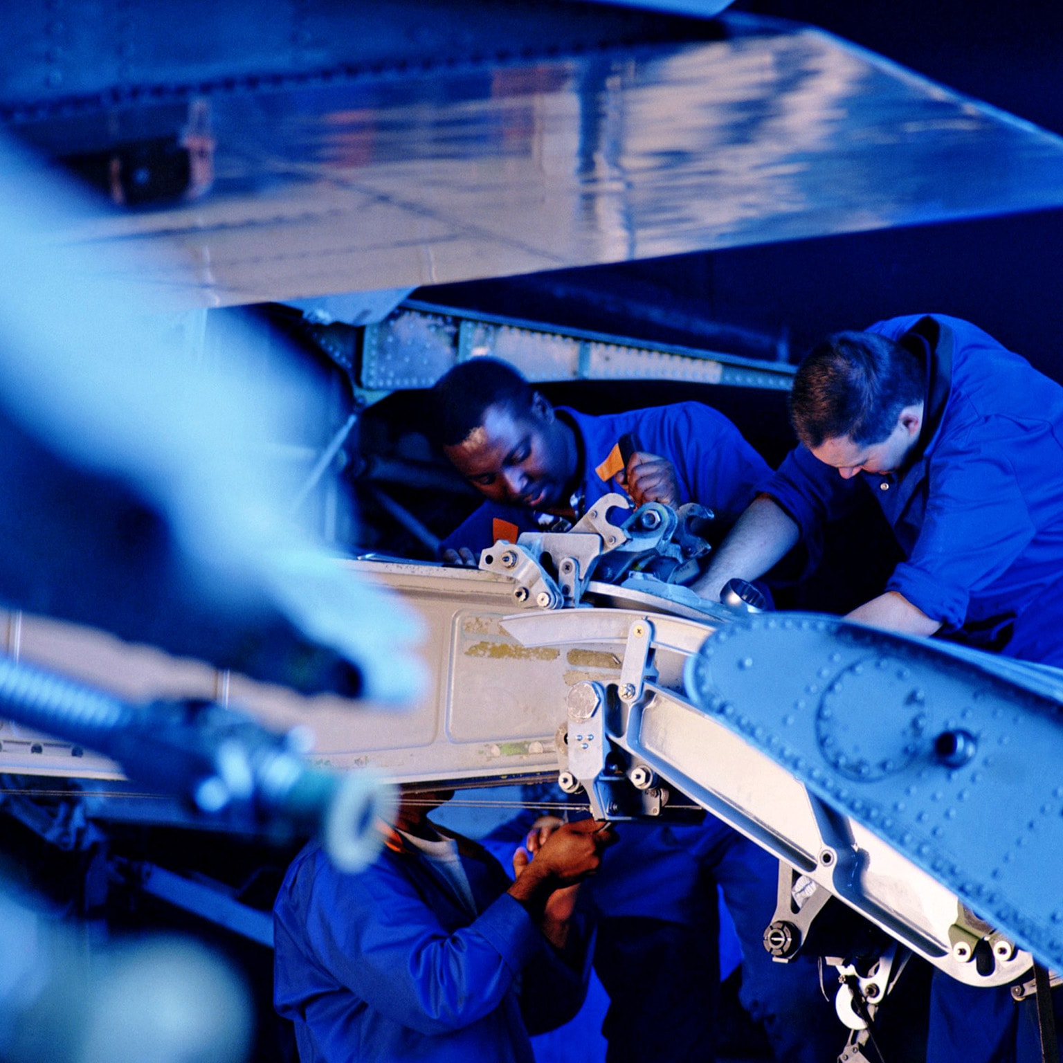 Flight engineers working on wing flap of airplane