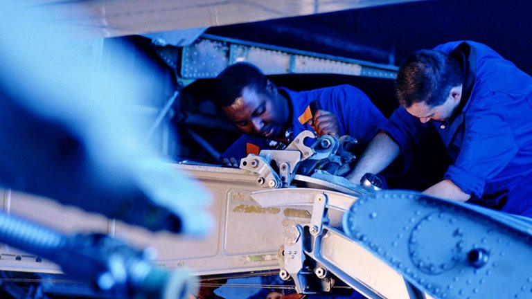 Flight engineers working on wing flap of airplane