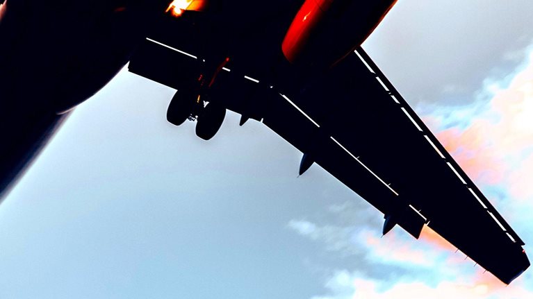 Close up view from below of an airplane flying upwards.