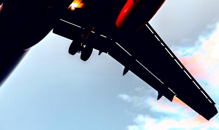 Close up view from below of an airplane flying upwards.
