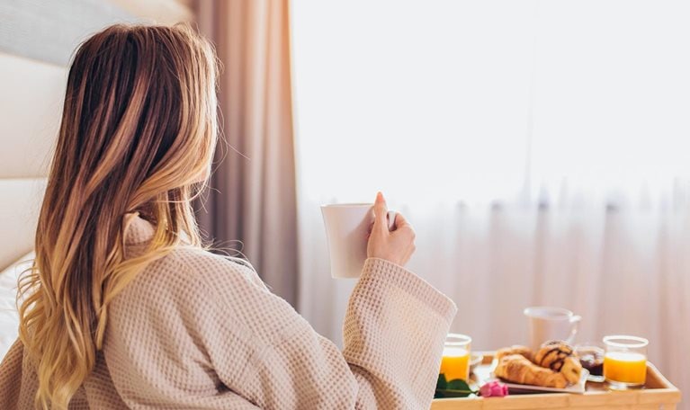 Woman laying and enjoying, breakfast in bed
