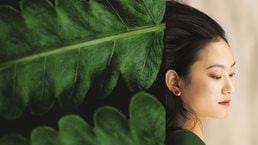 green leaves blending into side of woman's face - stock photo