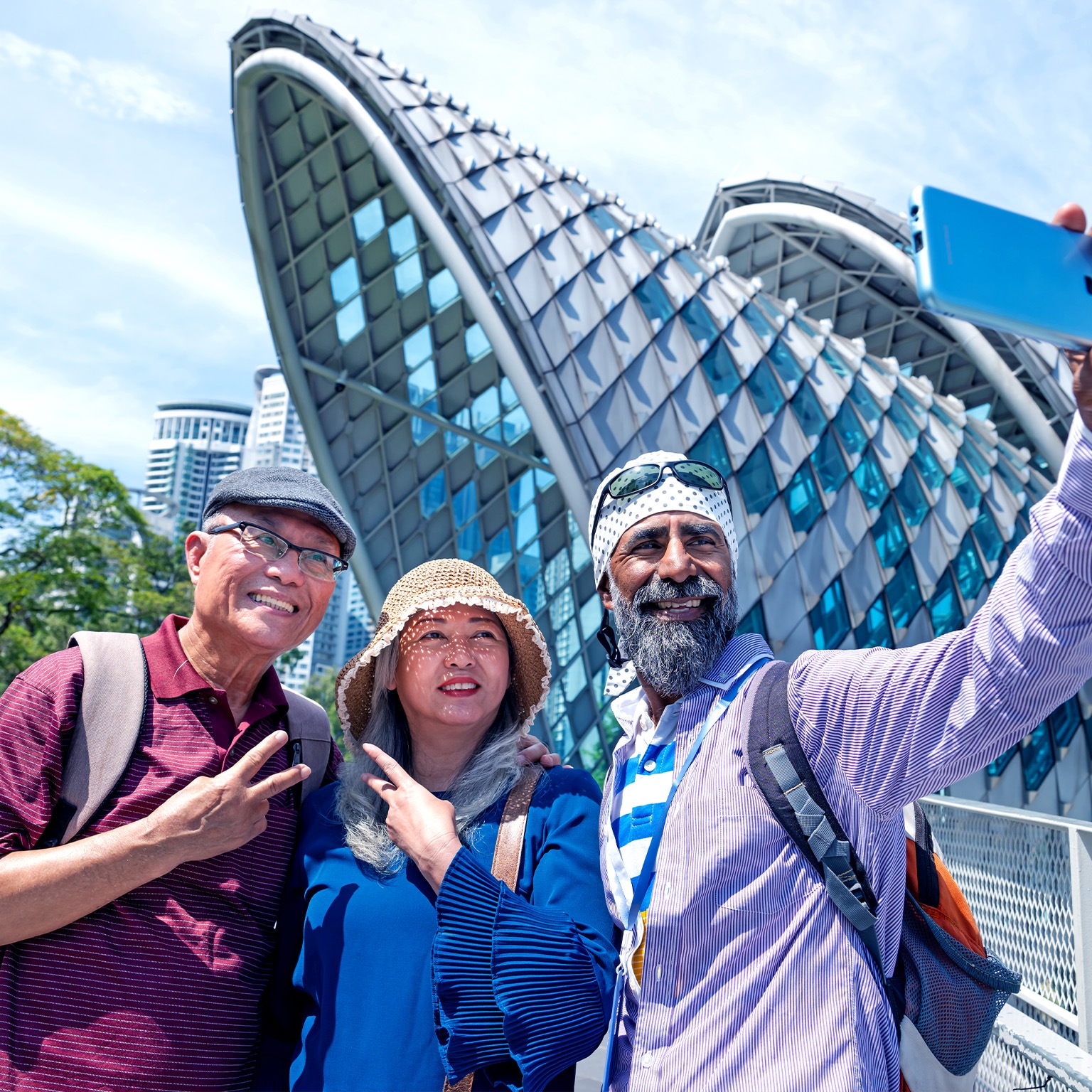 A senior Sikh tour guide and two senior Asian tourist taking selfie together in front the famous Saloma Bridge in the city of Kuala Lumpur.